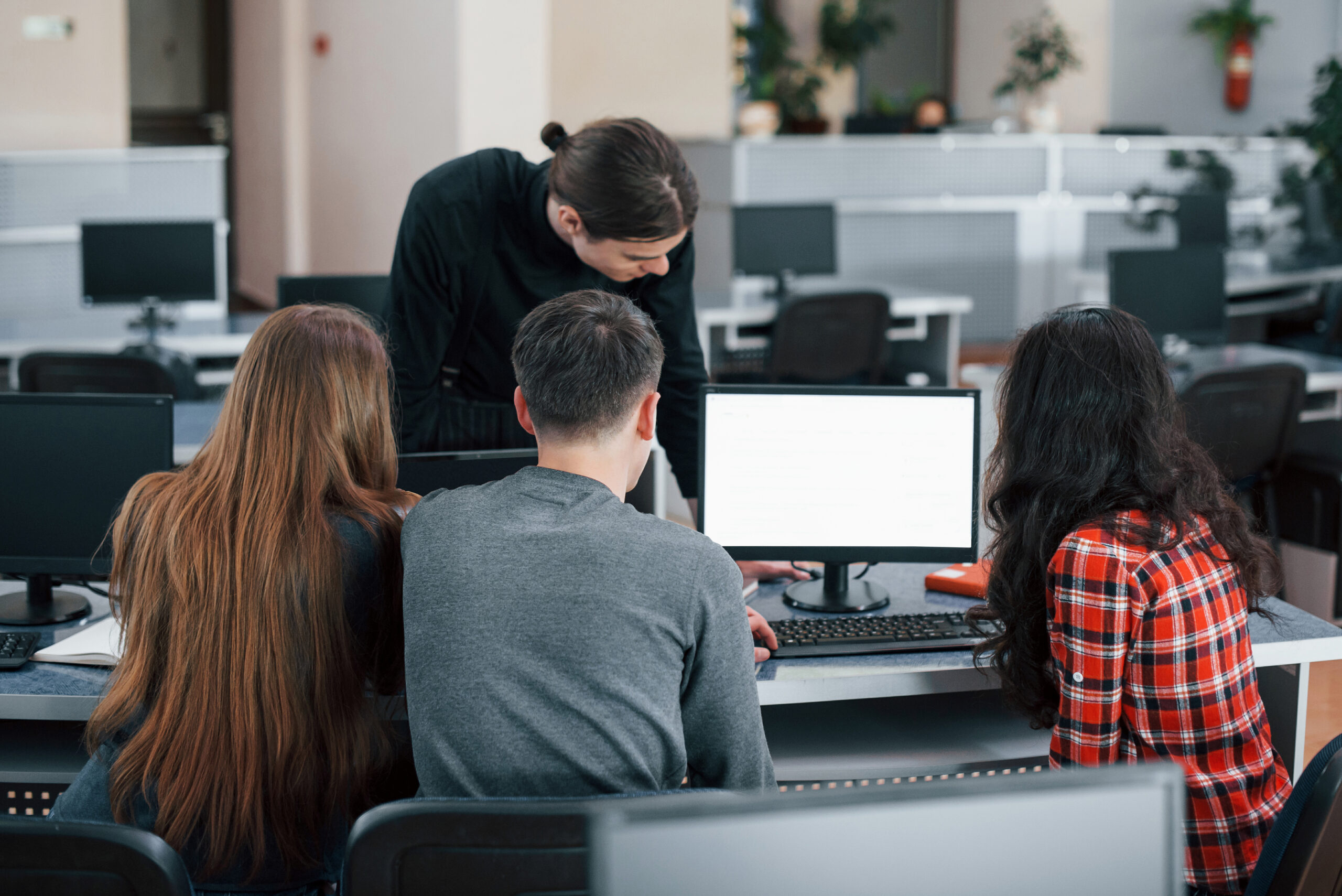 Screen with white color. Put your text there. Group of young people in casual clothes working in the modern office دوره الكمبيوتر - الصورة 1